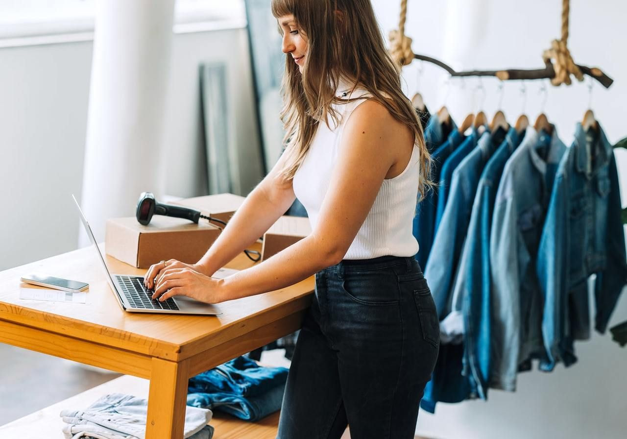 A woman using a laptop to find out how much does it cost to start a clothing brand.